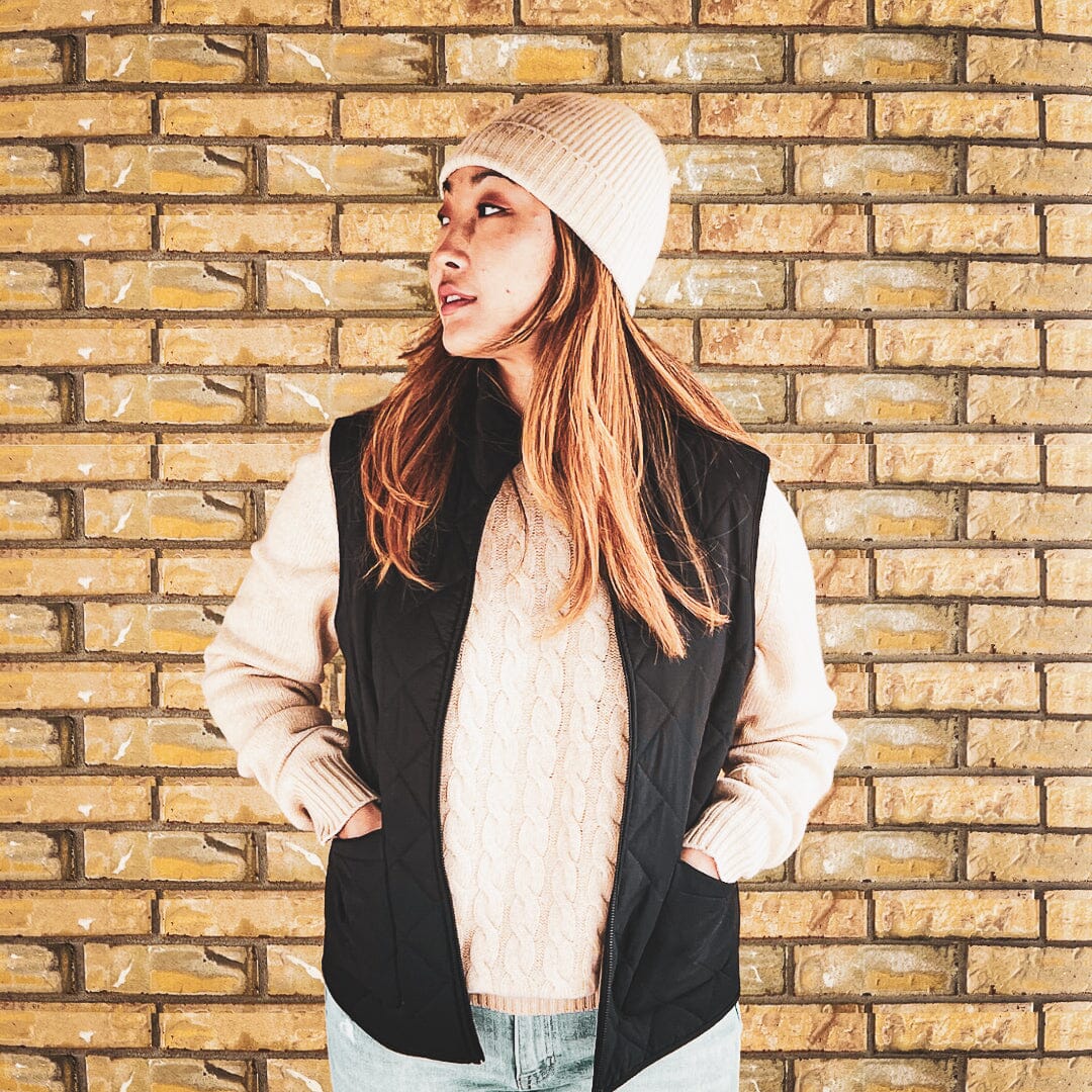 A woman modelling the Unisex Cashmere Vest in front of a brick wall